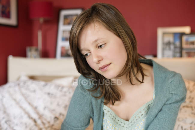 Adolescente sentada en la cama y pensando - foto de stock
