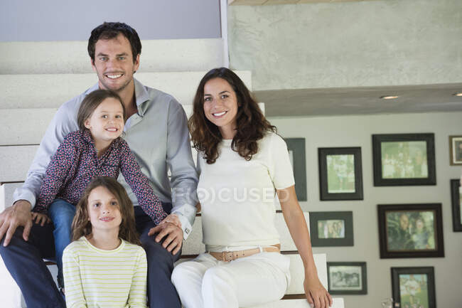 Famille assise sur les marches et souriant — Photo de stock