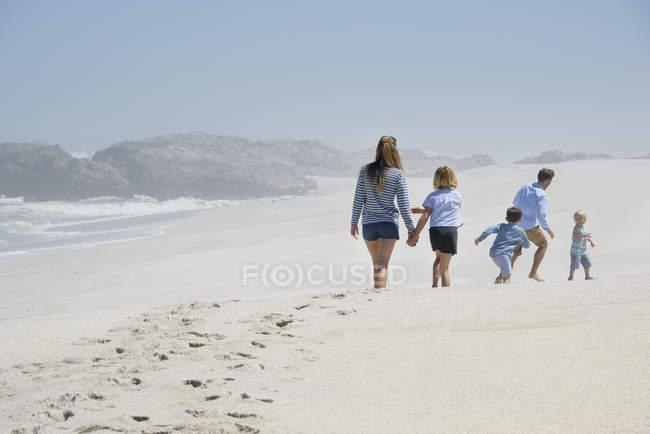 Rückansicht einer Familie, die am Strand spazieren geht — Stockfoto