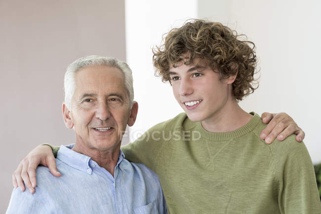 Porträt eines glücklichen älteren Mannes, der seinen Teenager-Enkel umarmt — Stockfoto