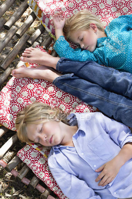 Cansados irmãozinhos dormindo na rede no jardim de verão — Fotografia de Stock