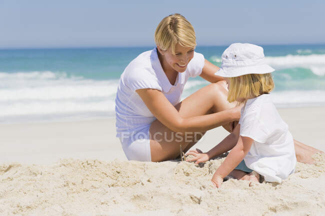 Mulher sentada com sua filha na praia — Fotografia de Stock