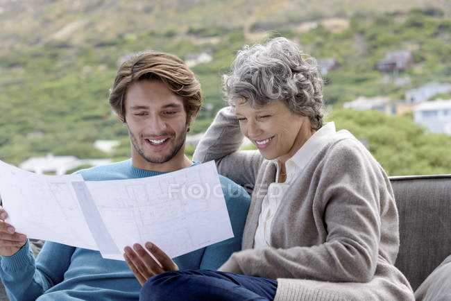 Mãe feliz com filho adulto lendo plantas ao ar livre — Fotografia de Stock