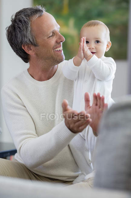 Happy father playing with cute baby daughter in living room — Stock Photo