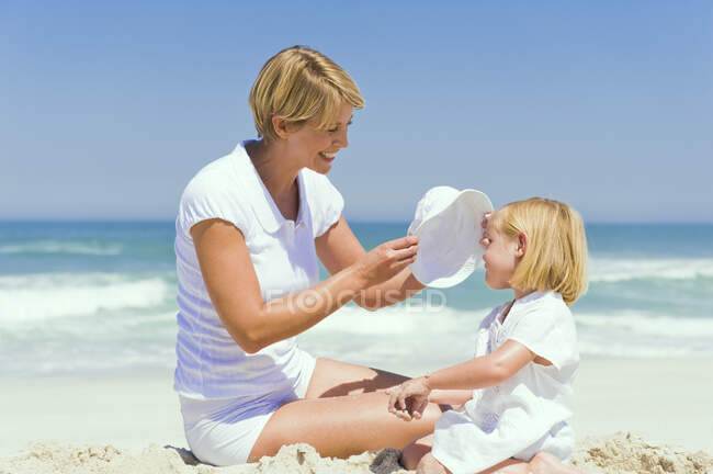 Женщина, сидящая со своей дочерью на пляже — стоковое фото