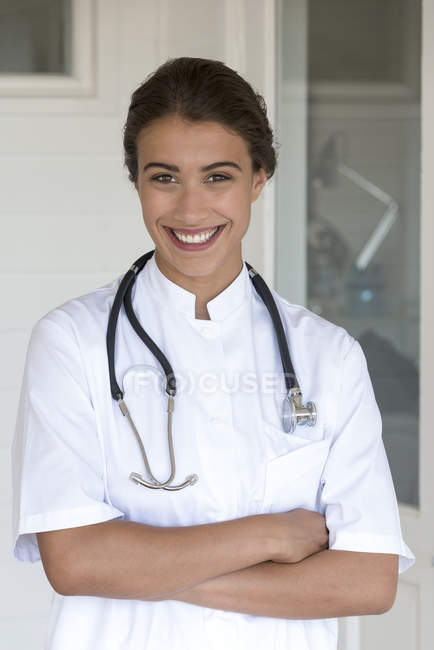 Portrait de femme heureuse médecin debout avec les bras croisés — Photo de stock