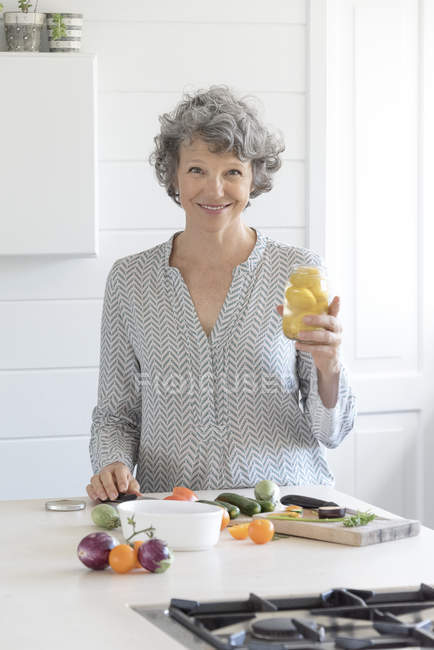 Retrato de mulher feliz segurando frasco na cozinha — Fotografia de Stock