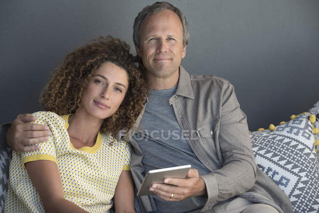 Портрет усміхненої пари, що сидить на дивані з цифровим планшетом — стокове фото