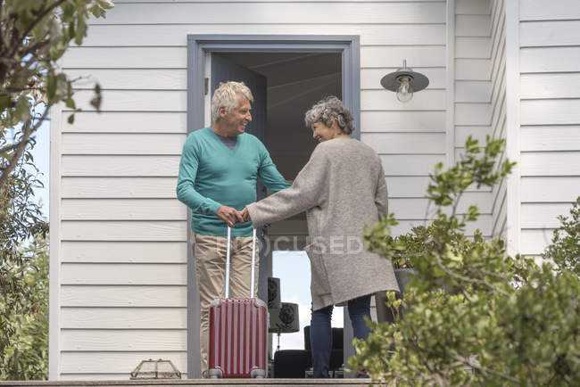Hombre mayor acogedora mujer en la puerta - foto de stock