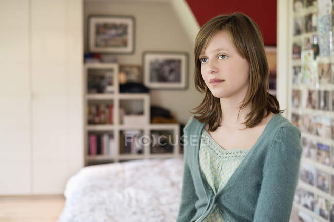 Teenage girl sitting on bed and thinking — Stock Photo