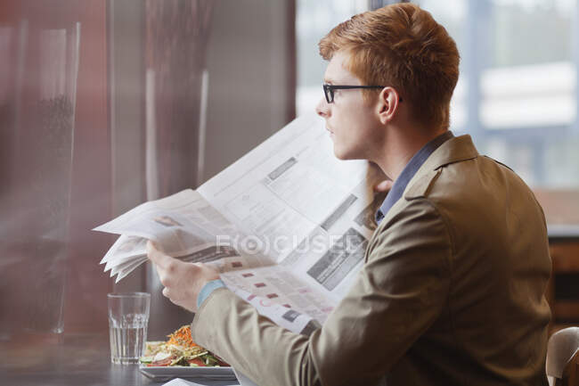 Mann sitzt in Restaurant und liest Zeitung — Stockfoto