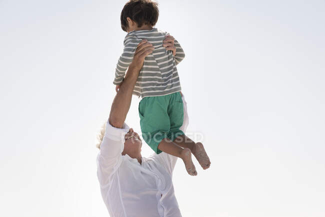 Счастливый дедушка играет с внуком на открытом воздухе — стоковое фото