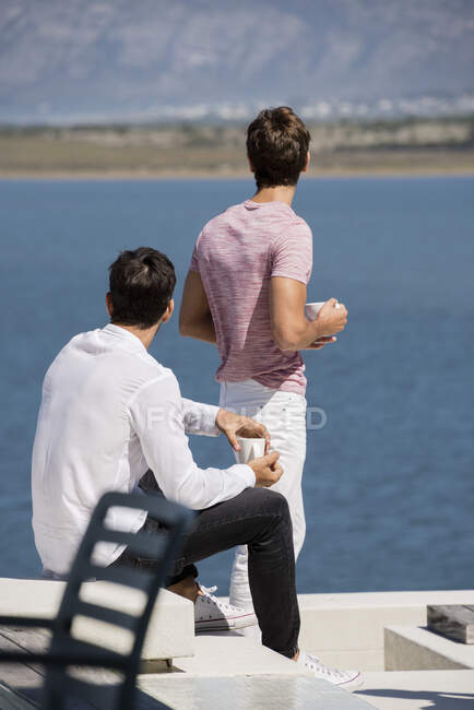 Dos amigos varones disfrutando del café juntos al aire libre - foto de stock
