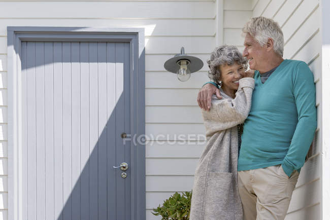 Romantic senior couple embracing outside of house — Stock Photo