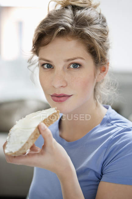 Retrato de mulher comendo torrada com creme de propagação — Fotografia de Stock