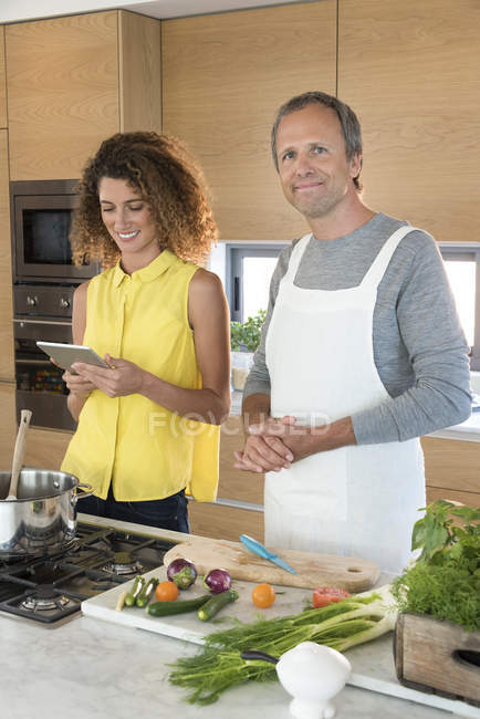 Счастливая пара готовит еду на кухне с цифровым планшетом — стоковое фото