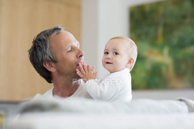 Pai feliz brincando com a filha bebê bonito na sala de estar — Fotografia de Stock