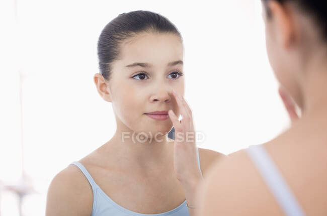Menina olhando seu rosto no espelho — Fotografia de Stock