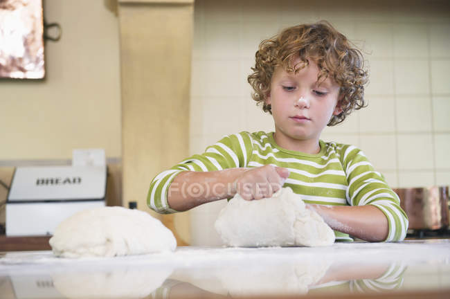 Bonito menino amassar massa na cozinha — Fotografia de Stock