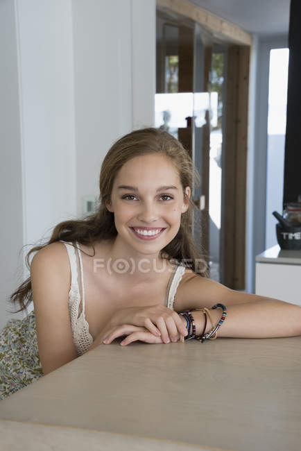 Портрет усміхненої дівчини-підлітка, що сидить за столом — стокове фото