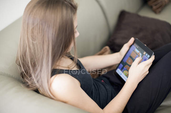 Дівчина-підліток використовує цифровий планшет на дивані вдома — стокове фото