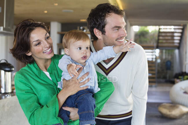 Padres sonriendo con su hijo en casa - foto de stock