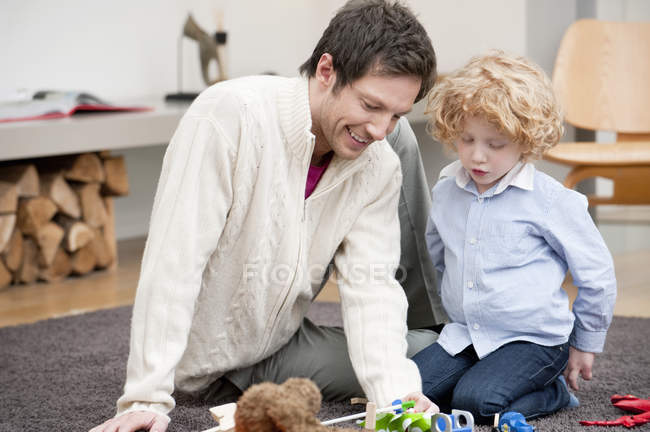 Homme jouant avec le petit fils sur le tapis à la maison — Photo de stock
