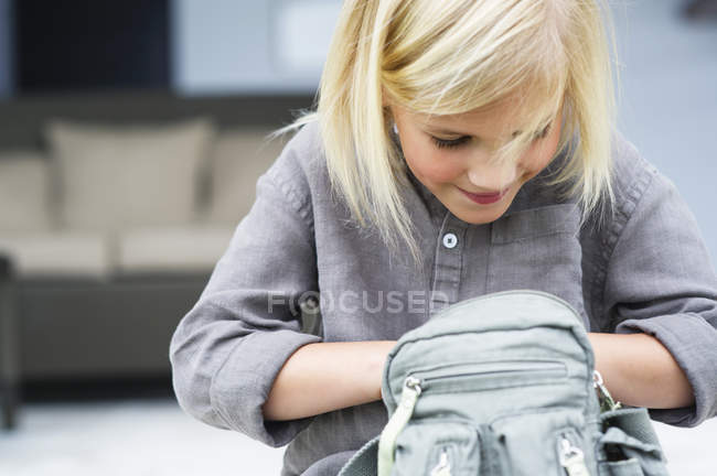 Kleines blondes Mädchen sucht in Tasche — Stockfoto