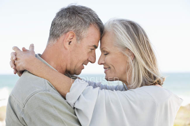 Romantic senior couple hugging on beach — Stock Photo