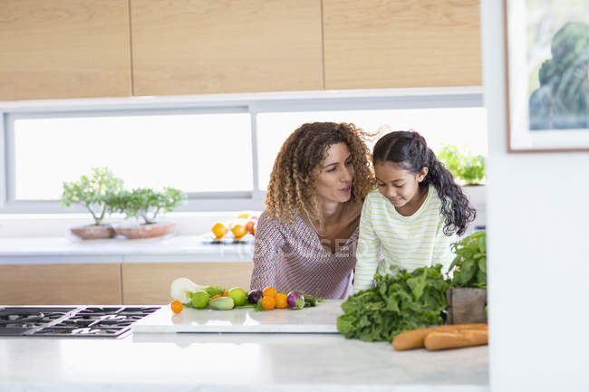 Junge Frau mit Tochter steht und spricht in Küche — Stockfoto