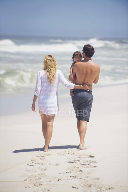 Счастливая семья, гуляющая на морском пляже — стоковое фото