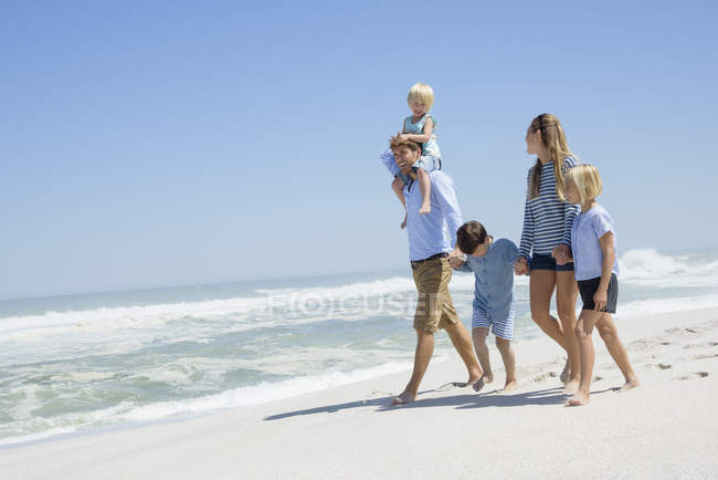 Счастливая семья с детьми, гуляющими на пляже — стоковое фото