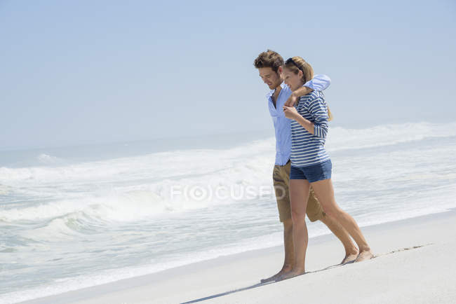 Романтическая пара, гуляющая по песчаному пляжу вместе — стоковое фото