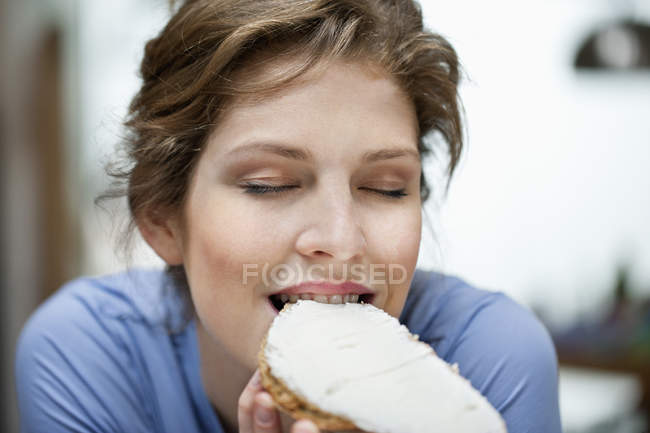 Porträt einer jungen Frau, die Toast mit Sahneaufstrich isst — Stockfoto