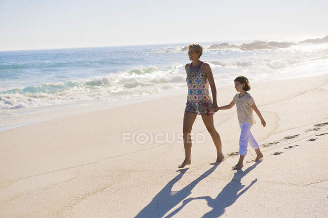 Жінка ходить на пляжі зі своєю дочкою — стокове фото