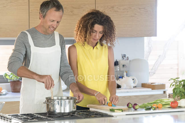 Casal feliz preparando comida na cozinha juntos — Fotografia de Stock