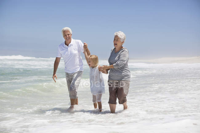 Girl having fun on sea beach with grandparents — Stock Photo