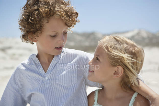 Крупный план брата и сестры, смотрящих друг на друга на пляже — стоковое фото