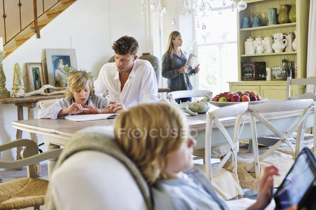 Hombre enseñando niño en casa con la familia en el fondo - foto de stock