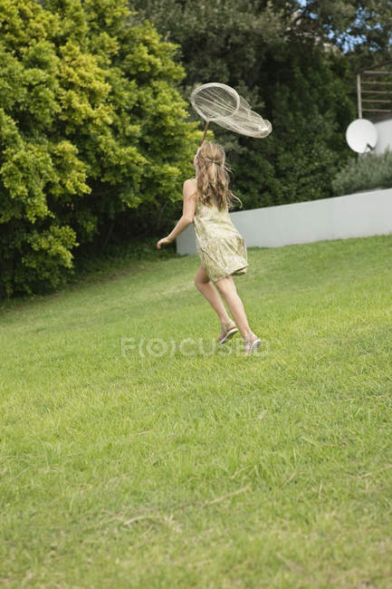Girl playing with butterfly net in summer garden — Stock Photo