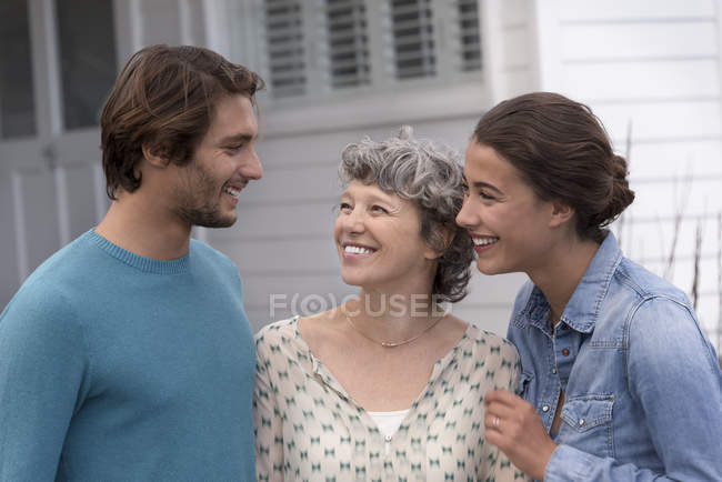 Счастливая зрелая женщина стоит с молодой парой на открытом воздухе — стоковое фото