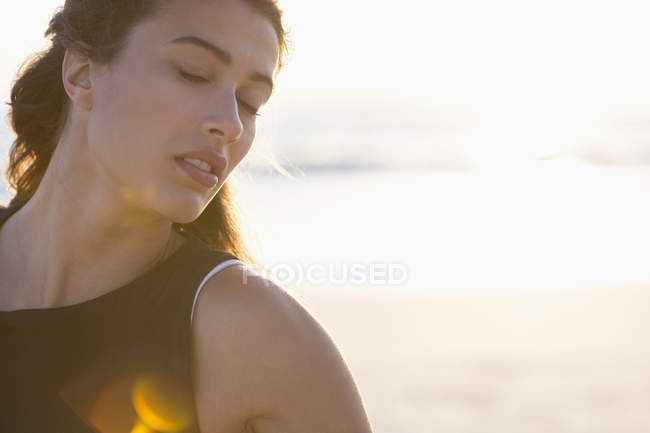 Чуттєва молода жінка з закритими очима позує на пляжі — стокове фото