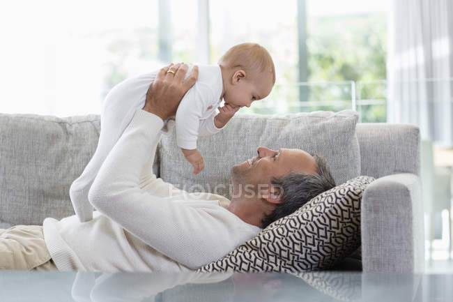 Щасливий батько, лежачи на дивані і граючи з милий дитина дочка вдома — стокове фото