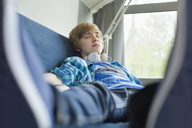 Adolescent garçon dormir sur canapé avec casque — Photo de stock