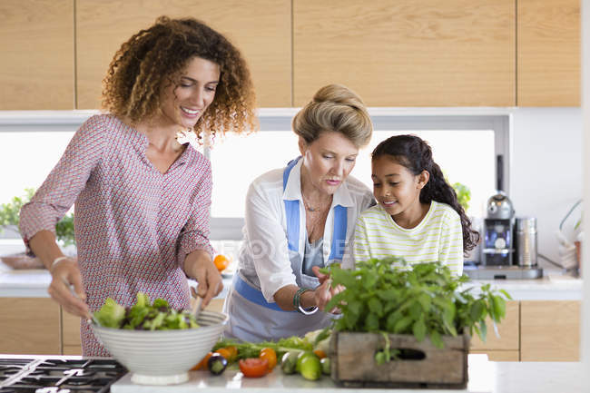 Seniorin mit Tochter und Enkelin bereitet Essen in Küche zu — Stockfoto