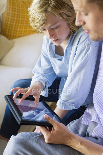 Чоловік і маленький хлопчик дивляться на цифровий планшет — стокове фото