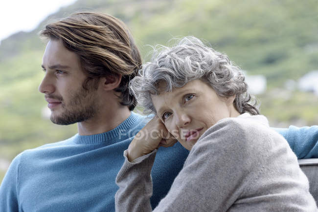 Мечтательная мать сидит со взрослым сыном на открытом воздухе — стоковое фото