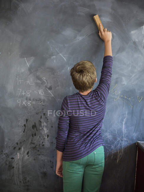 Junge putzt Tafel mit Staubwedel im Klassenzimmer — Stockfoto