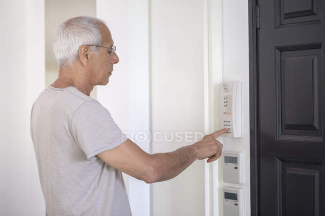 Homem sênior usando alarme anti-roubo na porta — Fotografia de Stock