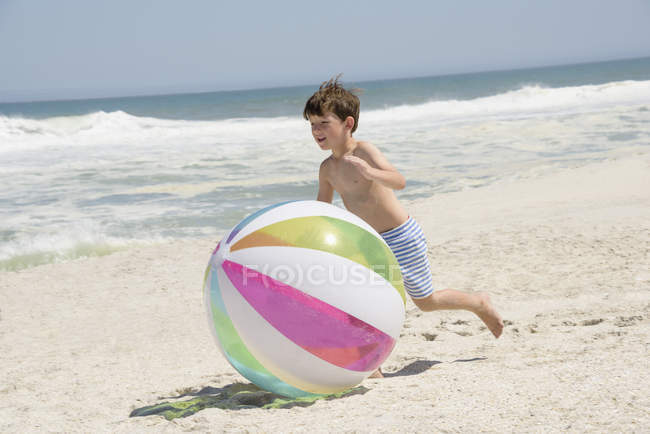 Garçon jouer avec la balle sur la plage de sable fin — Photo de stock